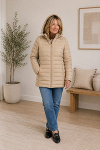 Woman wearing a beige puffer jacket in a home setting