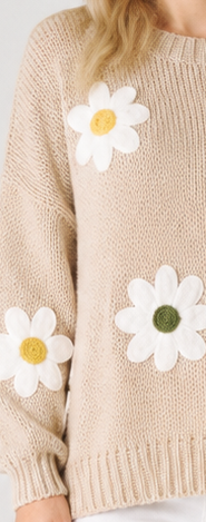 Beige knitted jumper with white daisy flower appliqués on a plain background