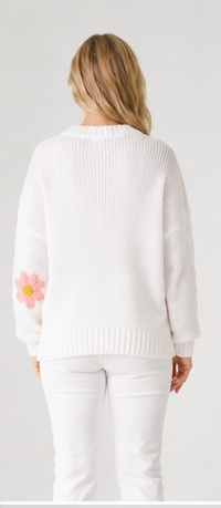 white knit jumper with a pink flower design on a plain back