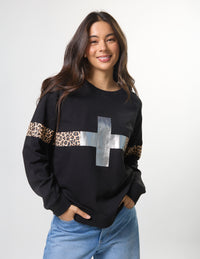 Woman wearing a black sweater with leopard print and silver cross design on a white background