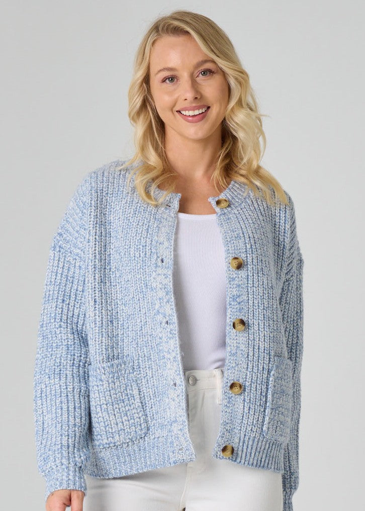 Woman wearing a light blue textured cardigan with wooden buttons on a plain background
