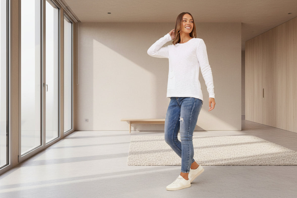 Woman wearing a white long-sleeve top and blue jeans 