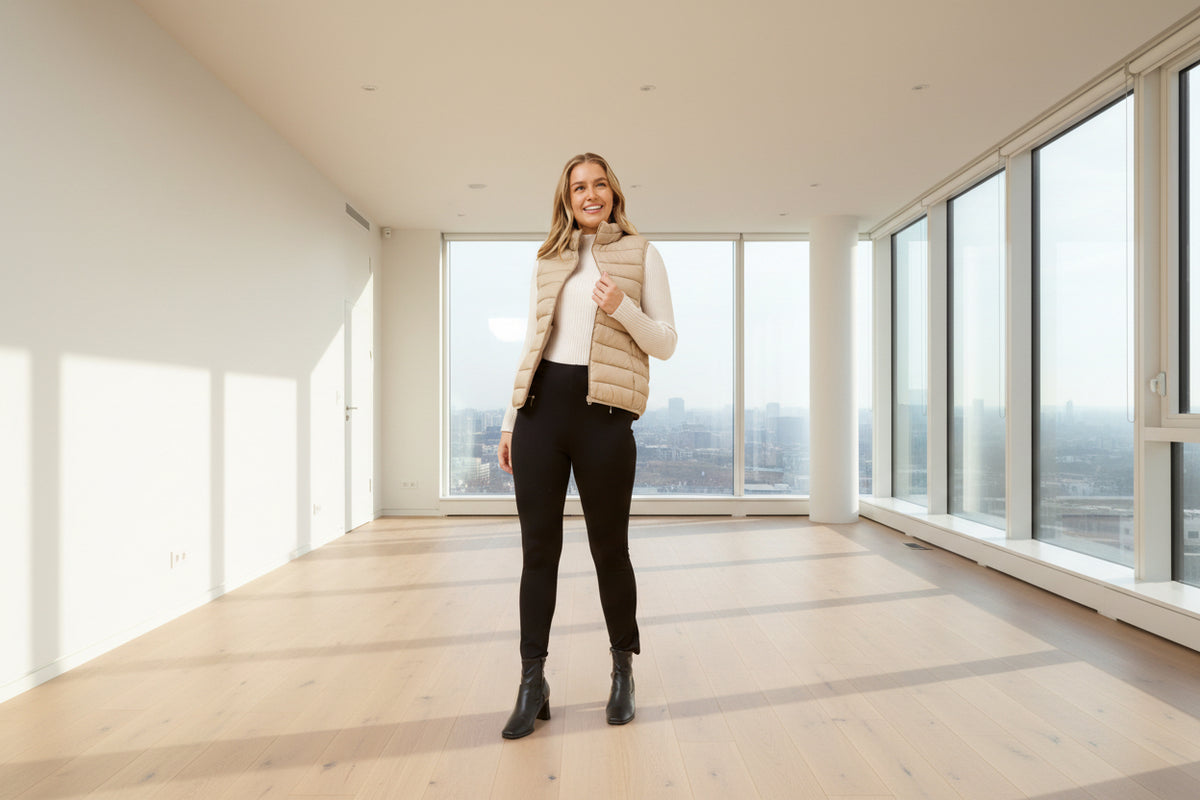 Woman wearing a beige puffer vest, white shirt, black pants, and black boots Pammy Puffer Vest