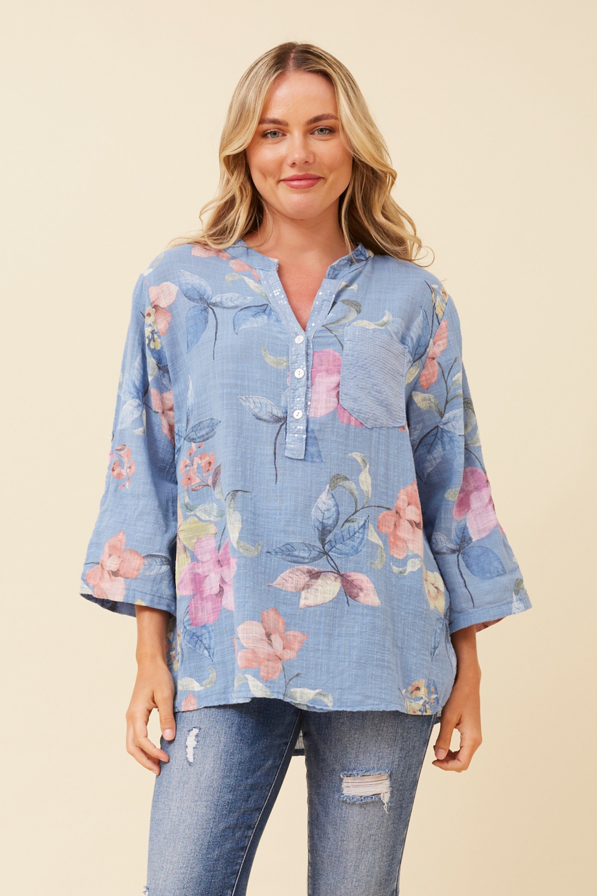 a light blue floral long-sleeve blouse with a button placket and 3/4 sleeves, paired with distressed blue jeans